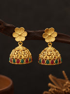 Gold earrings with floral design and colored stones on a dark background