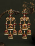 Ornate gold earrings with red and green gemstones on a dark background