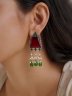 Close-up of an earring with red stone, green and blue beads, and pearl-like elements.