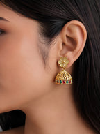 Gold earring with floral design and gemstones worn by a person