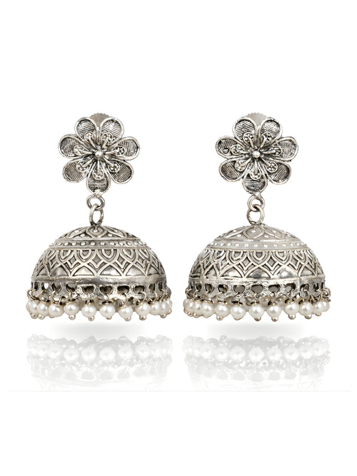 Pair of silver jhumka earrings with floral top and pearl drops on a white background