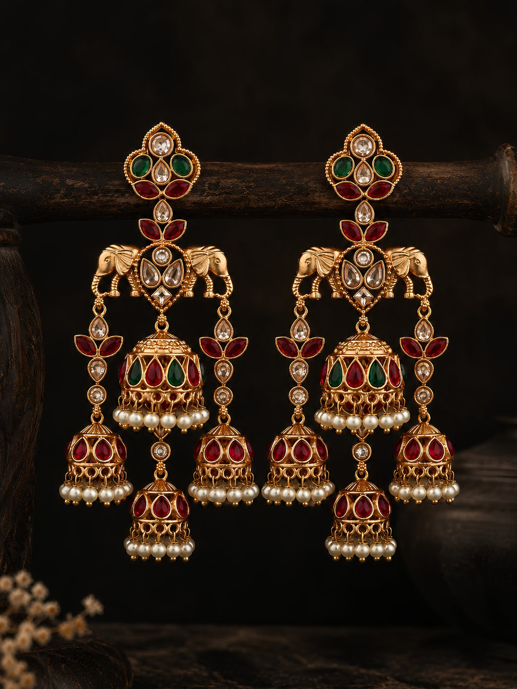 Pair of ornate gold earrings with gemstones on a dark background
