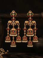 Pair of ornate gold earrings with gemstones on a dark background