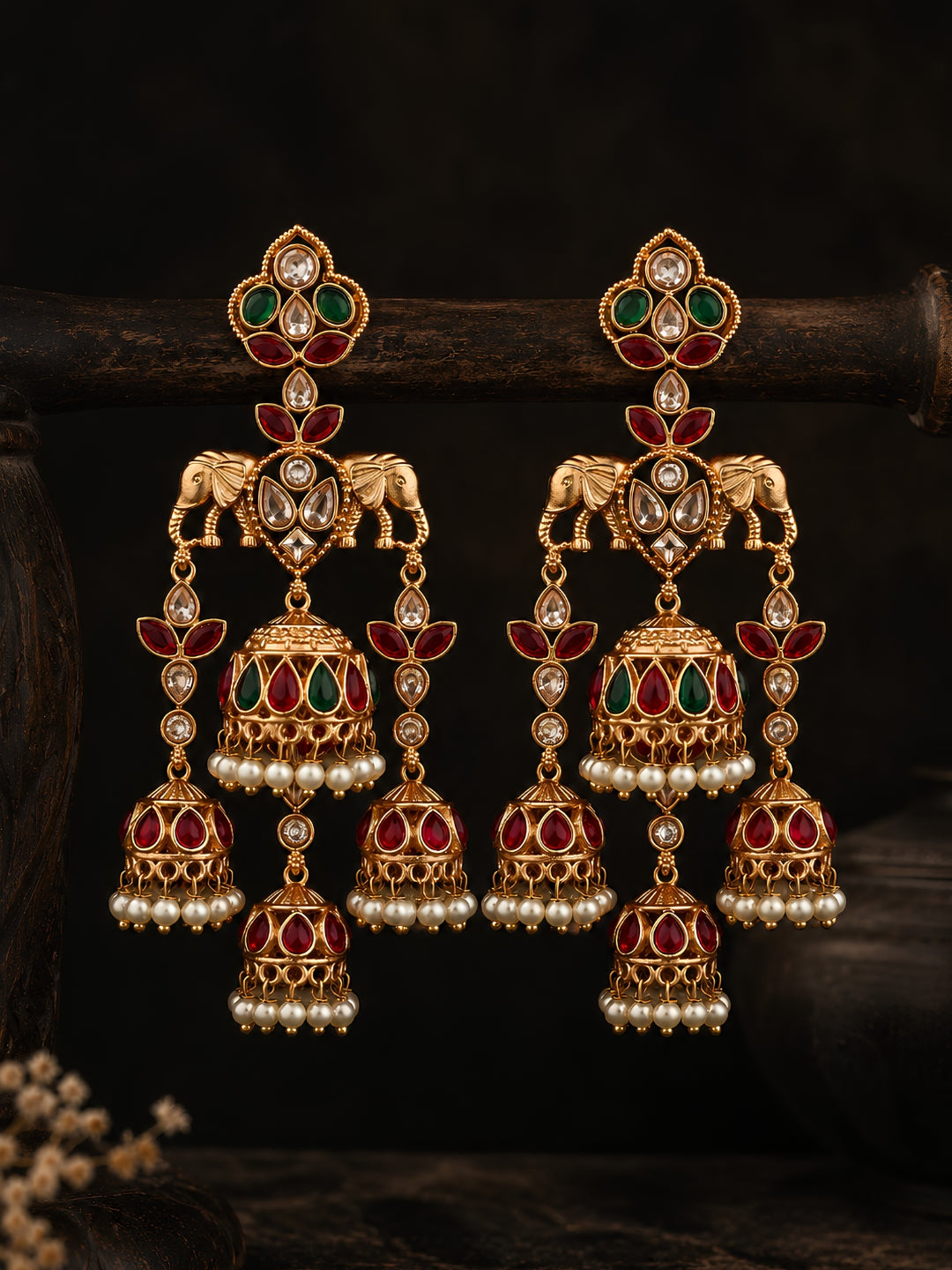 Pair of ornate gold earrings with gemstones on a dark background