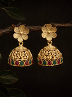 Gold floral earrings with red and green gemstones on a dark background