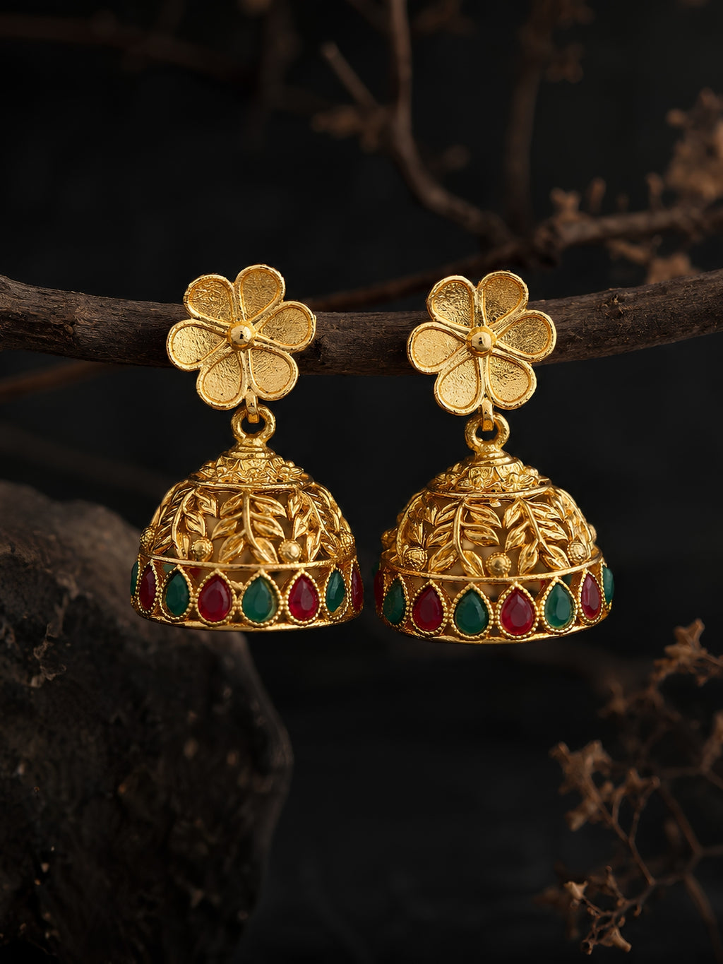 Gold floral earrings with colored stones on a dark background