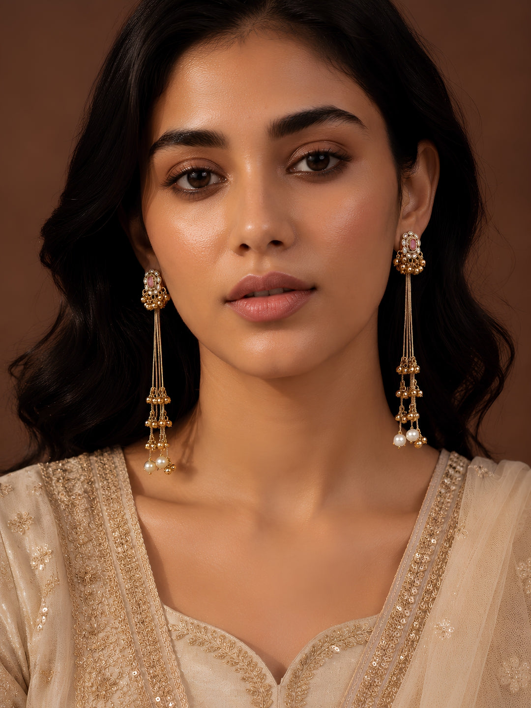 Woman wearing gold earrings with a plain background