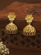 Gold earrings with floral designs on a wooden surface