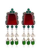Pair of earrings with red central stones, green accents, and pearl-like beads on a white background